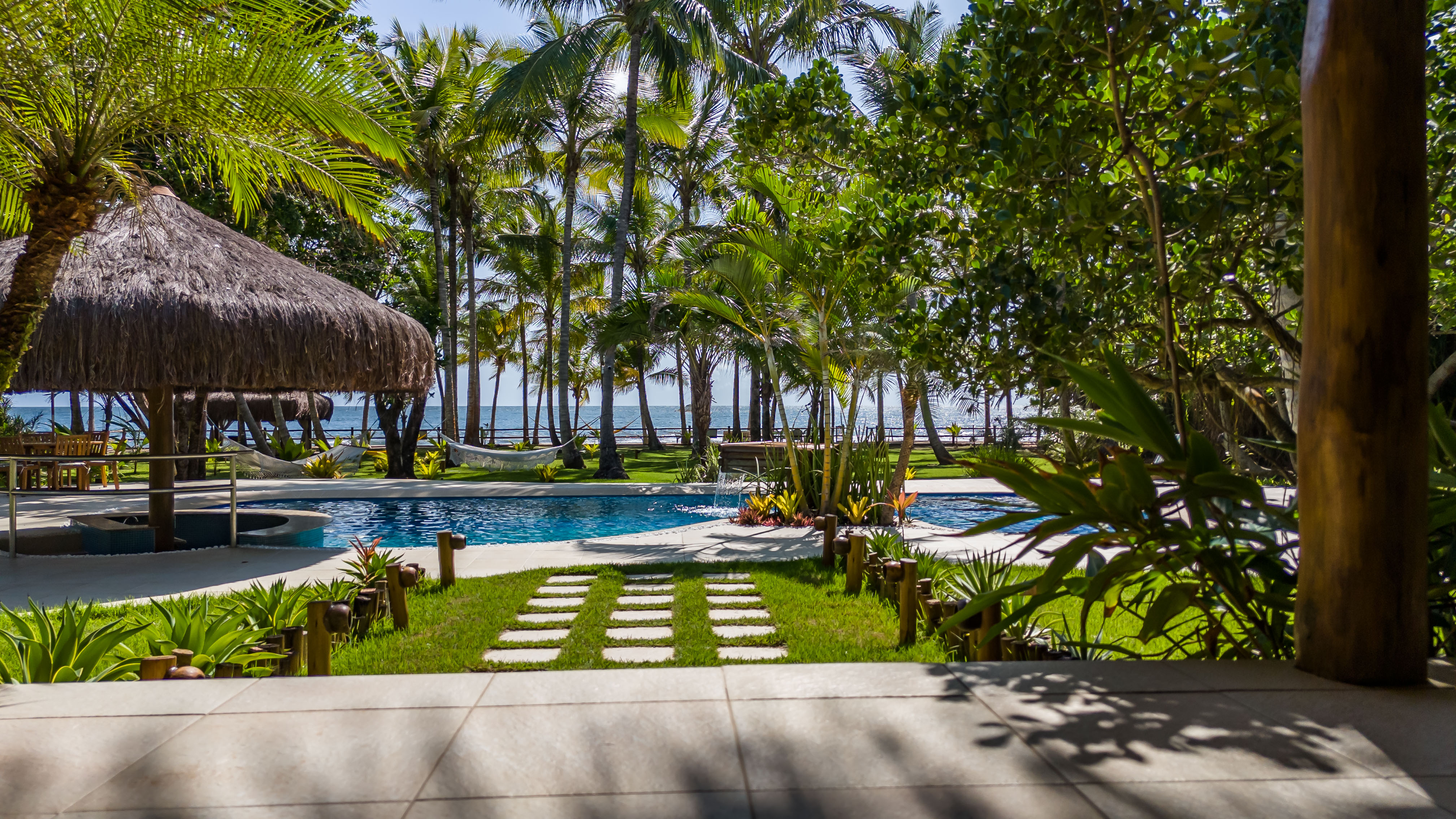 Piscina de águas cristalinas com bar molhado integrado ao coqueiral